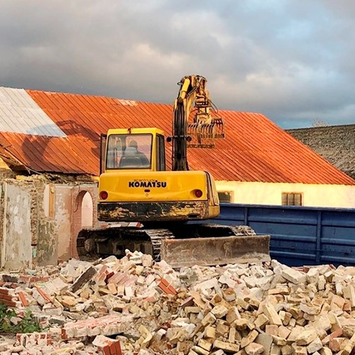 Maskine som er ved at udføre nedbrydning af et hus som var lavet ud af mursten.